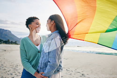 Image of Gay, flag and lesbian couple at the beach for travel, freedom and bond, care and happy in nature together. Rainbow, love and women on ocean vacation embrace lgbt, partner or pride, date or acceptance