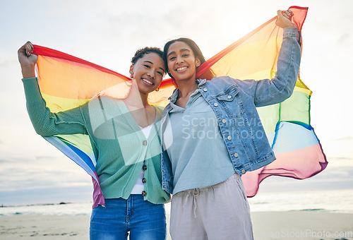 Image of Woman, lesbian couple and pride flag on beach together in happiness for LGBTQ community or rights. Portrait of proud and confident gay or bisexual women smile on ocean coast in love, support or trust