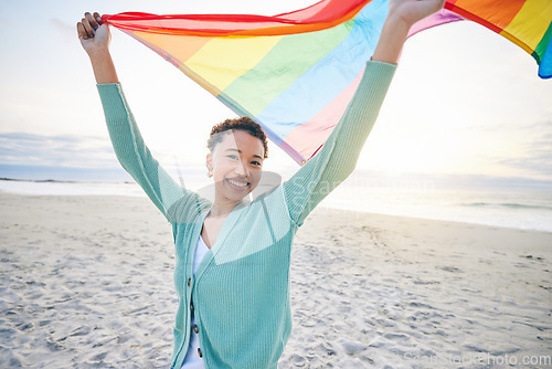 Image of Woman, beach and pride flag for lgbtq in portrait, smile and wind with wave, rainbow and equality for inclusion. African girl, fabric or cloth for human rights, lesbian sexuality or happy on vacation