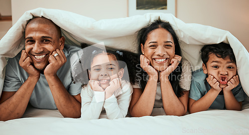 Image of Happy, love and portrait of a family in bed with a blanket relaxing, resting and bonding at home. Happiness, smile and young children laying with their mother and father in the bedroom of their house