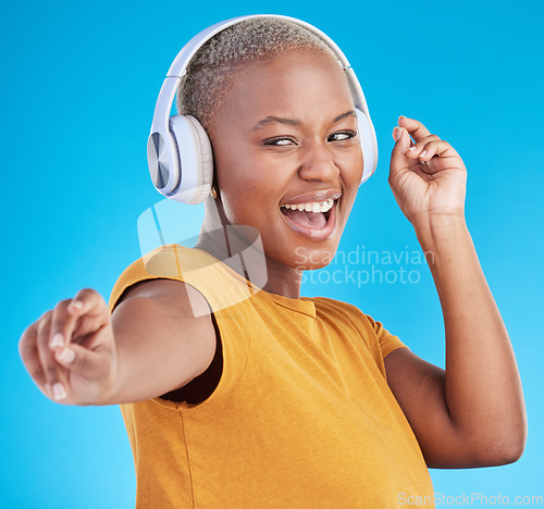 Image of Black woman, headphones and dance, listen to music and energy with happiness isolated on blue background. Female person, wireless tech and radio with fun, dancer with freedom and streaming in studio