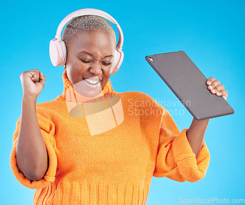 Image of Winner, success or black woman in studio with tablet, achievement or bonus on blue background. Headphones, giveaway or happy person with technology in celebration of reward, prize or online victory