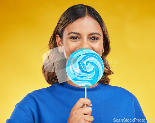 Image of Lollipop, candy and portrait of woman with sweet dessert with sugar isolated in a studio yellow background with smile. Food, snack and young person with delicious treats, product or guilty pleasure