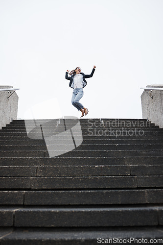 Image of Business person, stairs and jump for celebration, success and goals in finance career, investment and stock market. Young woman, winner and fist in air for achievement, pride or lottery on city steps