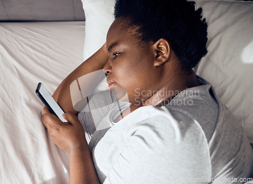 Image of Stress, morning or black woman in bed with phone for social media lying in room for addiction at home. Insomnia, lonely or sad person reading online to scroll on mobile app in bedroom with depression