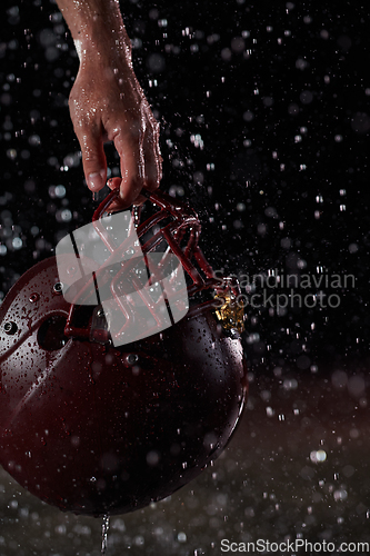 Image of Close up of American Football Athlete Warrior Standing on a Field focus on his Helmet and Ready to Play. Player Preparing to Run, Attack and Score Touchdown. Rainy Night with Dramatic lens flare