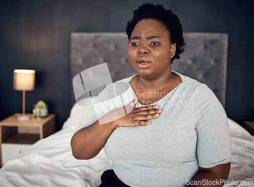 Image of Fear, sick and a black woman with an anxiety attack or pain in chest from stress. Scary, health and an African girl on a bed with panic, depression or a mental health illness or fail in the bedroom