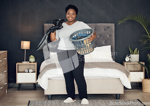 Image of Black woman, clothes in basket and cleaning bedroom, garbage bag and hygiene with portrait in bedroom. Female person, cleaner and housekeeping with smile, laundry and maintenance with morning routine