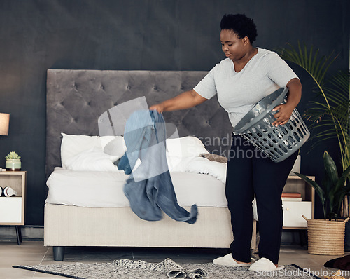 Image of Black woman, clothes with basket and cleaning bedroom, organize mess with hygiene and hospitality. Female person, cleaner and housekeeping, busy with laundry and maintenance with morning routine