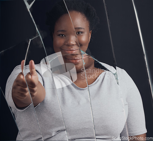 Image of Healing, success and woman portrait with thumbs up in broken mirror after depression and stress in studio. Face, smile and African female abuse survivor emoji hand for feedback on bipolar treatment