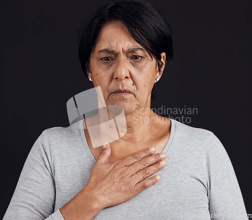 Image of Fear, senior and a woman with a heart attack on a black background with healthcare anxiety. Emergency, sad and an elderly person feeling chest for pain, sick or medical scare isolated on a backdrop