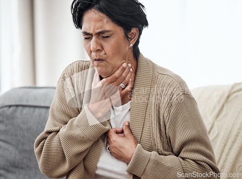 Image of Senior woman, cough and sick on sofa in home, chest pain and pneumonia with tuberculosis or choke. Pensioner, mature lady or sore throat with lung infection, breathing problem and choking with asthma