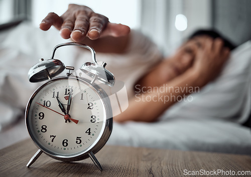 Image of Alarm, morning and a hand with a clock for awake, oversleep or tired in the bedroom of a home. House, ring and a closeup of a person or woman in bed for snooze, rest or waking up lazy in a house