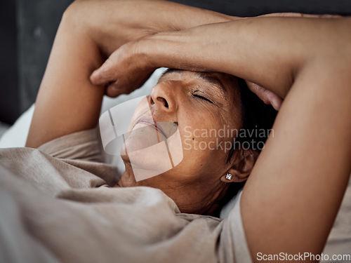 Image of Sleeping, headache and senior woman in home bedroom with fatigue, tired or exhausted. Depression, insomnia and elderly person in bed with pain, stress and problem, anxiety or crisis in retirement