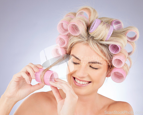 Image of Hair care, curlers and young woman in a studio doing a natural, beautiful and curly hairstyle. Self care, happy and attractive female model with rollers for beauty isolated by a gray background.