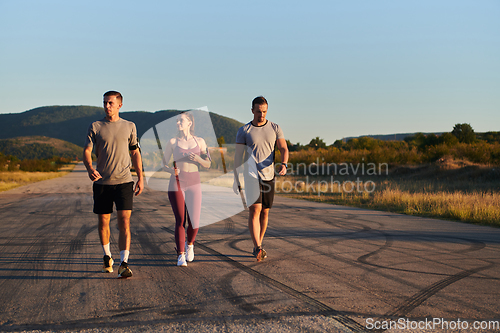 Image of A group of young athletes running together in the early morning light of the sunrise, showcasing their collective energy, determination, and unity