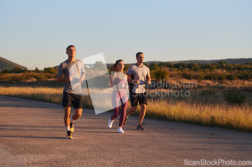 Image of A group of young athletes running together in the early morning light of the sunrise, showcasing their collective energy, determination, and unity