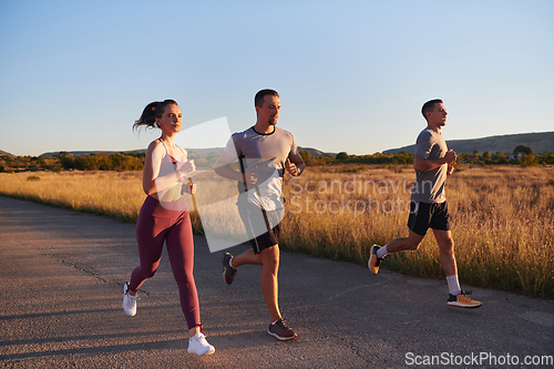 Image of A group of young athletes running together in the early morning light of the sunrise, showcasing their collective energy, determination, and unity