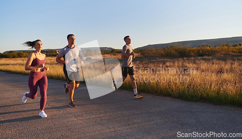 Image of A group of young athletes running together in the early morning light of the sunrise, showcasing their collective energy, determination, and unity