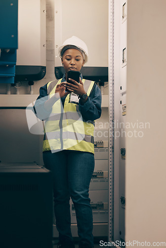 Image of Black woman, engineering and electrician on cellphone in control room for system maintenance, industrial mechanic and inspection. Female technician, mobile technology and planning electrical services