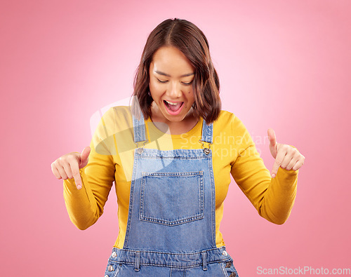 Image of Excited, pointing and young woman in a studio for marketing, promotion or advertising. Shock, surprise and Asian female model with presentation or showing finger gesture isolated by a pink background