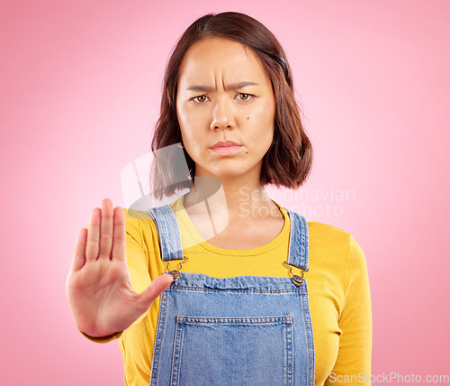 Image of Woman, hand and stop in studio portrait with angry face, rejection or bad review by pink background. Gen z student girl, icon or emoji for protest, voice or opinion for feedback, activism or warning