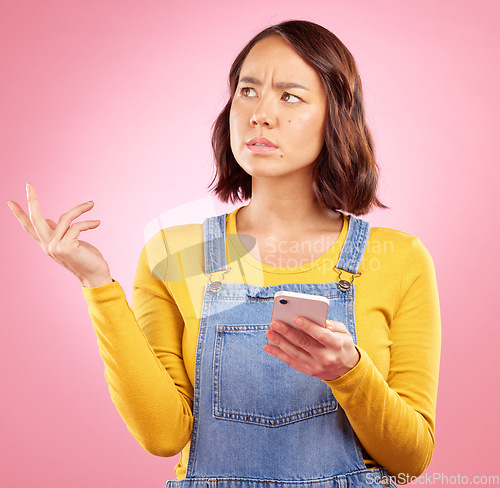 Image of Thinking, studio and Asian woman with cellphone problem, bad news and stress over mistake, crisis or social media post. Frustrated, doubt and person confused over smartphone glitch on pink background