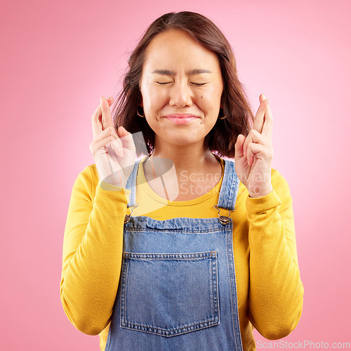 Image of Woman, fingers crossed and hope for success in studio, pink background or praying for good luck. Asian model, hands and wish for bonus, giveaway winner or emoji sign for competition prize in lottery