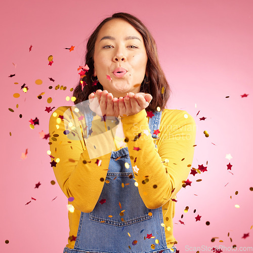 Image of Portrait, celebration and woman blow confetti to celebrate winner announcement, congratulations and New Years cheers. Studio, winning or Asian person happy for birthday party event on pink background