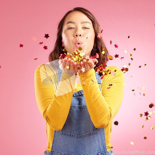 Image of Portrait, celebration and Asian woman blow confetti to celebrate winner, happiness and excited at party event. Studio color, wow and creative Japanese person happy for birthday on pink background