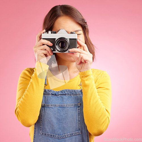 Image of Photographer woman, retro camera and studio for shooting, memory or paparazzi job by pink background. Journalist girl, photoshoot and lens for newspaper, gossip magazine or content creator for blog