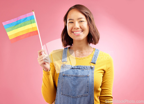 Image of Woman, pride flag and studio portrait for smile, lgbtq goals and vote for love by pink background. Gen z student girl, gay icon or symbol for protest, voice or opinion for power, equality and rainbow