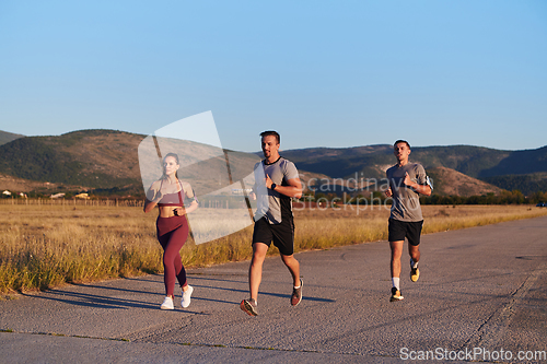 Image of A group of young athletes running together in the early morning light of the sunrise, showcasing their collective energy, determination, and unity