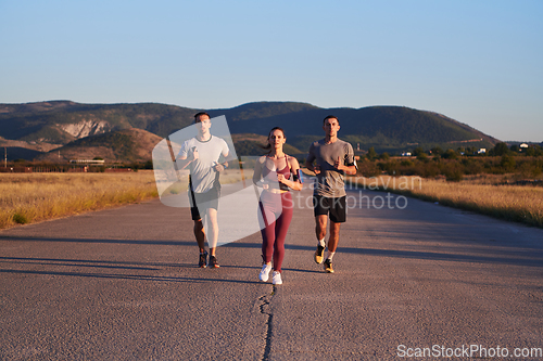 Image of A group of young athletes running together in the early morning light of the sunrise, showcasing their collective energy, determination, and unity