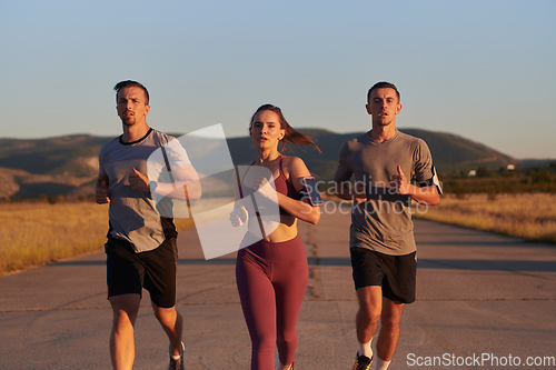 Image of A group of young athletes running together in the early morning light of the sunrise, showcasing their collective energy, determination, and unity