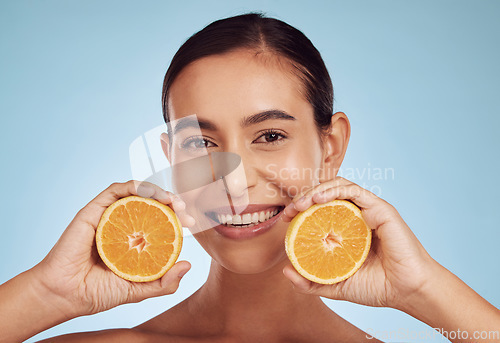 Image of Happy woman, portrait and smile with orange vitamin C, skincare or diet against blue studio background. Female person with organic citrus fruit for natural nutrition, dermatology or healthy wellness