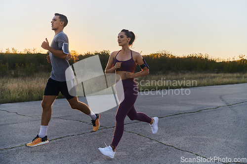 Image of A handsome young couple running together during the early morning hours, with the mesmerizing sunrise casting a warm glow, symbolizing their shared love and vitality