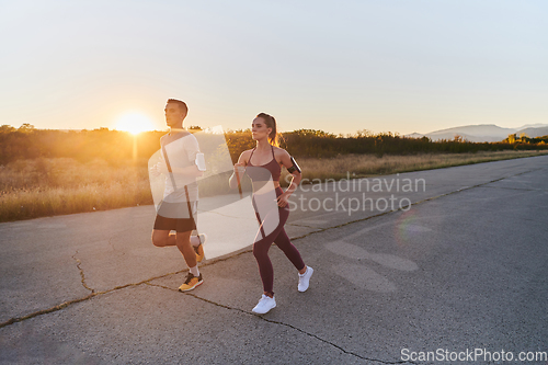 Image of A handsome young couple running together during the early morning hours, with the mesmerizing sunrise casting a warm glow, symbolizing their shared love and vitality