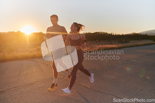 Image of A handsome young couple running together during the early morning hours, with the mesmerizing sunrise casting a warm glow, symbolizing their shared love and vitality