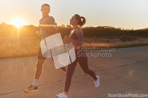 Image of A handsome young couple running together during the early morning hours, with the mesmerizing sunrise casting a warm glow, symbolizing their shared love and vitality