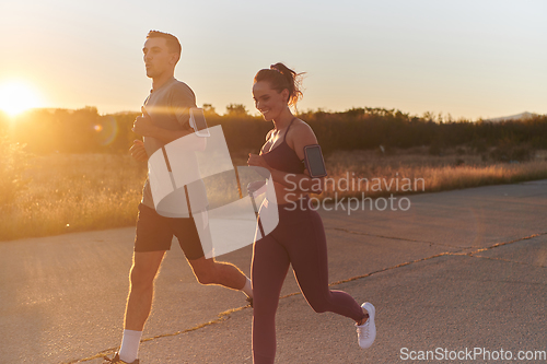 Image of A handsome young couple running together during the early morning hours, with the mesmerizing sunrise casting a warm glow, symbolizing their shared love and vitality