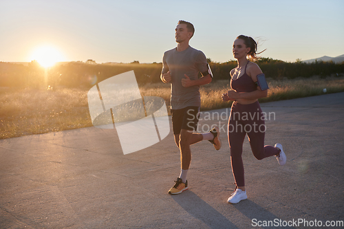 Image of A handsome young couple running together during the early morning hours, with the mesmerizing sunrise casting a warm glow, symbolizing their shared love and vitality