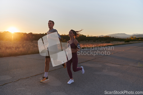 Image of A handsome young couple running together during the early morning hours, with the mesmerizing sunrise casting a warm glow, symbolizing their shared love and vitality