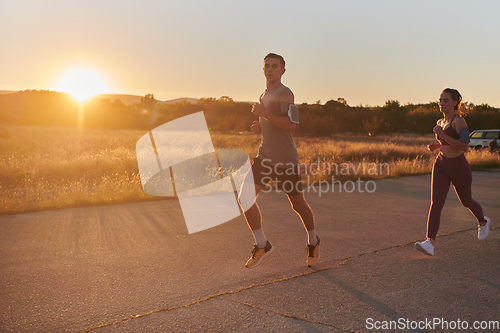 Image of A handsome young couple running together during the early morning hours, with the mesmerizing sunrise casting a warm glow, symbolizing their shared love and vitality