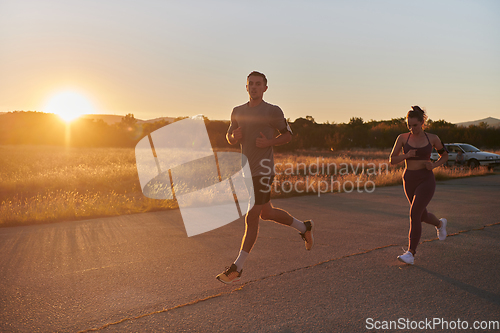 Image of A handsome young couple running together during the early morning hours, with the mesmerizing sunrise casting a warm glow, symbolizing their shared love and vitality