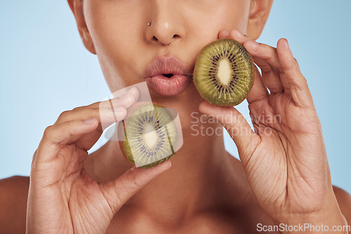 Image of Fruit, pout and woman with kiwi for skincare or organic dermatology treatment isolated in a blue studio background. Skin, beauty and young female person with facial wellness, nutrition and detox