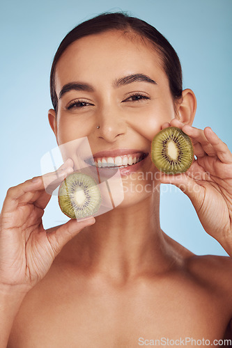 Image of Beauty portrait, kiwi and woman for skincare, cosmetics and natural product, facial health and vitamin c. Face of young happy person or model, green fruits and dermatology on studio, blue background