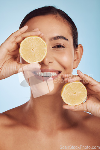 Image of Happy woman, skincare portrait and lemon for beauty, cosmetics, natural facial product and vitamin c benefits. Face of young person or model with fruits for eye dermatology on studio, blue background