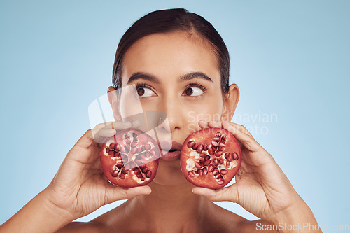 Image of Face, skincare and woman with pomegranate for beauty in studio isolated on a blue background. Natural cosmetic, fruit and model with food for nutrition, healthy vegan diet and vitamin c for wellness.