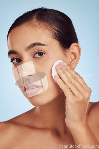 Image of Woman, face and cotton pad for skincare or makeup removal against a blue studio background. Portrait of female person with swab for cleaning foundation, beauty cosmetics or facial skin treatment